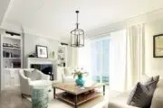 White living room with tub chair, coffee table and fireplace, with cage lantern light fixutre