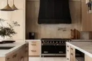 black matte range hood in a kitchen with wooden cabinet and gold fixtures